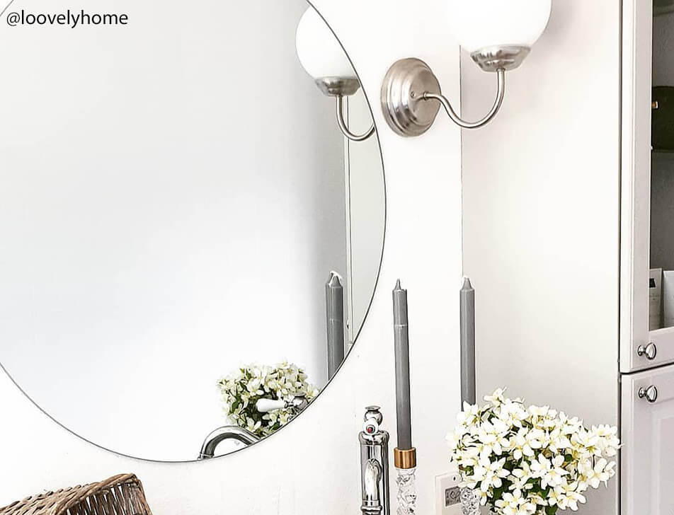 Kerek tükör, virágok és gyertyák a fürdőszobában